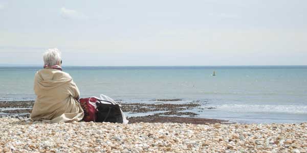 Lady sat on Lyme Regis beach looking out to sea